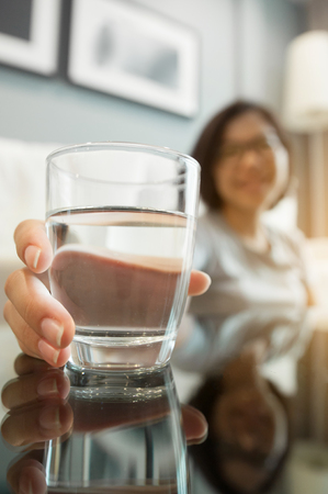 Asian glasses woman holding glass of water for drink. Woman smiling. Happiness, fresh.の写真素材