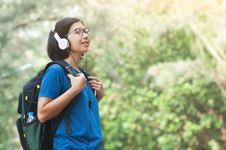 Happiness of Young Asian woman hiker with backpack listening music with headphone in nature.
Beautiful glasses girl closed her eyes and smiling with fresh air.の写真素材
