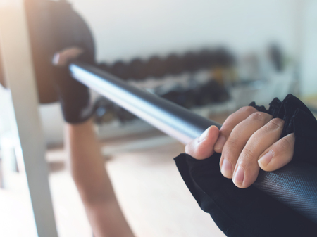 Close up man hands wear gloves with barbell at the gym.の写真素材