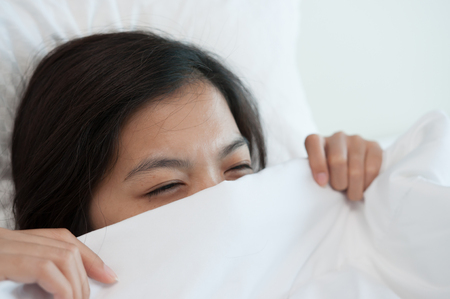 Happiness of young Asian woman lying with blanket on bed in the morning. Winter day.  Copy space.の写真素材