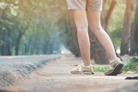 Woman hitchhiker walking on highway road with sunlight.の写真素材