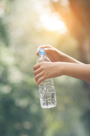 Close up Asian woman hand holding bottle of water on nature background. copy space. Traveler.の写真素材