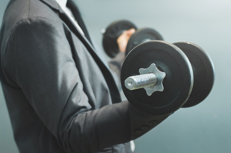 Wellness, healthy concepts. Businessman lifting dumbbell at office.の写真素材