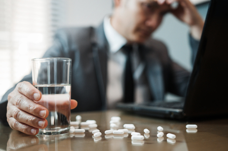 Illness, stressed, tired, exhausted, pain from overworked concepts. Asian Businessman holding glass of water with pills. Man has  migraine.の写真素材