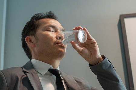 Asian Businessman in grey suit drinking water. Healthy. Copy space.の写真素材