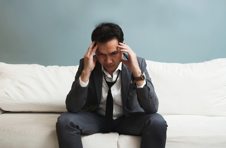 Exhausted, Illness, tired, stressed from overworked concepts. Businessman in grey suit has headache from migraine.の写真素材