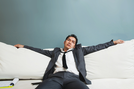 Exhausted, Illness, tired, stressed from overworked concepts. Businessman in grey suit sit on sofa.の写真素材