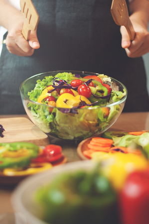 Woman cooking salad with vegetables.の写真素材