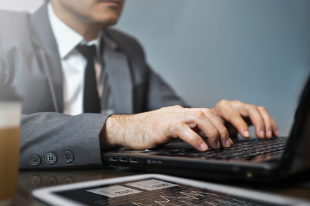Close up Asian Businessman in grey suit using and typing on laptop. Man looking to laptop.の写真素材
