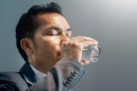 Asian Businessman in grey suit drinking water. Healthy. Copy space.の写真素材