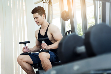 Asian Muscular man lifting dumbbells in gym. copy space.の写真素材