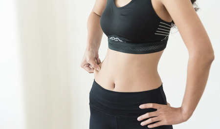 Young Asian woman pinched her belly on white isolated background. Slim girl with copy space.の写真素材