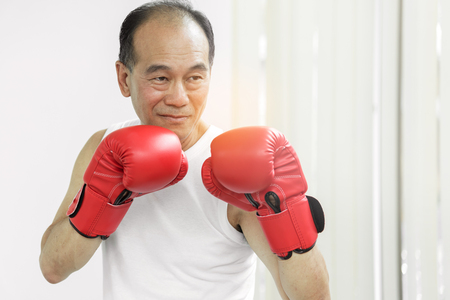 Portrait of Asian senior fighter man with red boxing gloves on white background.の写真素材