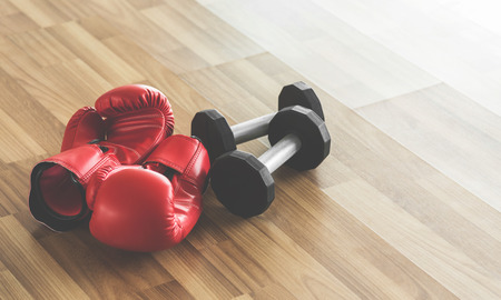 Red boxing gloves with dumbbells on wooden floor. Copy space.の写真素材