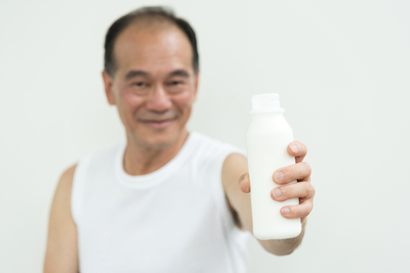 Asian senior man holding bottle of milk.の写真素材