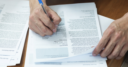 Close up of Man hand with pen writing and signing on Model release document form.