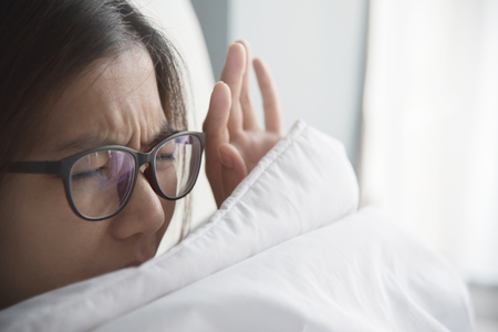 Asian woman having trouble about getting up early in the morning.の写真素材