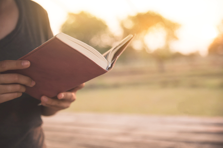 Girl reading a book on countryside background.の写真素材