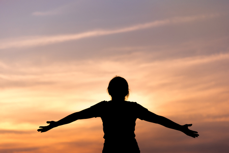 Silhouette young woman relaxing in  sunset sky outdoor. Happiness.の写真素材