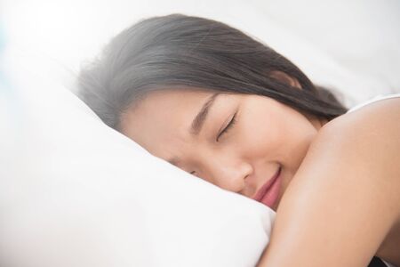 Asian beautiful woman sleeping on her bed. Happiness Girl smiling on morning.の写真素材