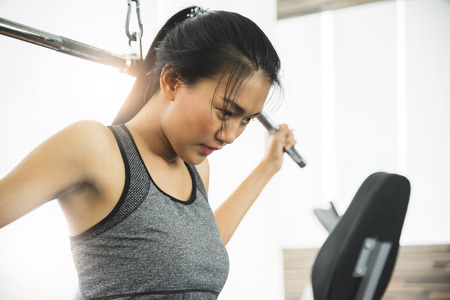 Asian woman in sportswear exercising with exercise machine at the gym.
