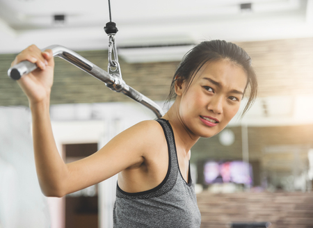 Asian woman in sportswear exercising with exercise machine at the gym.