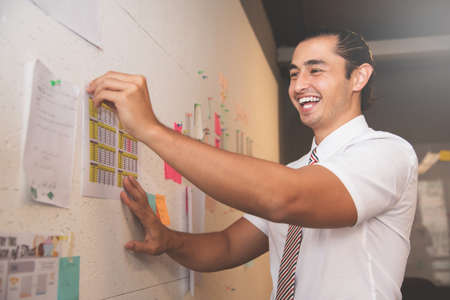 Happines of Businessman smiling and preparing documents on wall for meeting in office.の写真素材