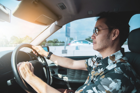 Portrait of Asian man wear sunglasses driving a car.の写真素材