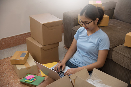 Young Asian woman looking to order details on a laptop in her small warehouse. Own businessの写真素材