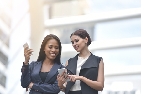 Portrait of Business colleagues women using mobile phone together at outdoor.の写真素材