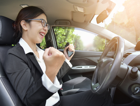 Relaxed Asian Business girl in glasses celebrate with raised hands up in a car. Success and Happy Concept. Smiling face.の写真素材
