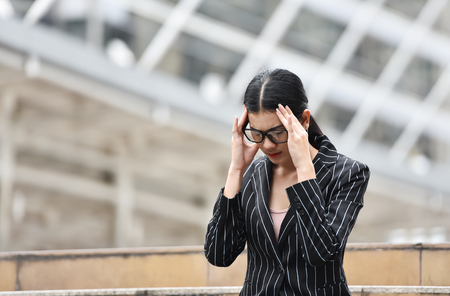 Stressed Asian Business woman having headache from overtime working at outdoor. Copy space.の写真素材