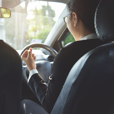 Rear view of Relaxed Asian Business girl in glasses celebrate with raised hand up in a car. success and happy Concept. Smiling face.の写真素材