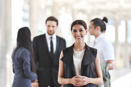 Portrait of confident Beautiful Business Woman standing and looking at the camera with business people background. Copy space. Smiling face.の写真素材