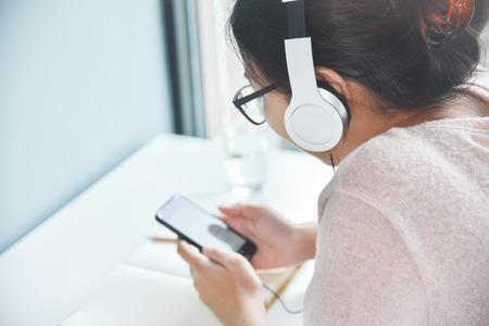 Happy Beautiful Asian woman listening to the music with headphone 
and mobile phone at her bedroom. Copy space.の写真素材