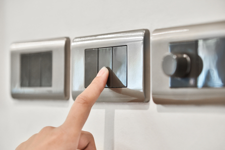 Close up hand turning on or off on grey light switches. Copy space.の写真素材