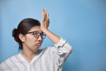 Tired Asian glasses woman having headache. Copy space. Migraine from Overtime working. Diseases, Illness concept.の写真素材