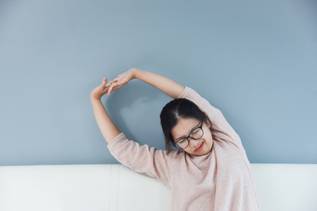 Happy Asian woman in Glasses Outstretched arms on blue wall  background at her bedroom. Copy space.の写真素材