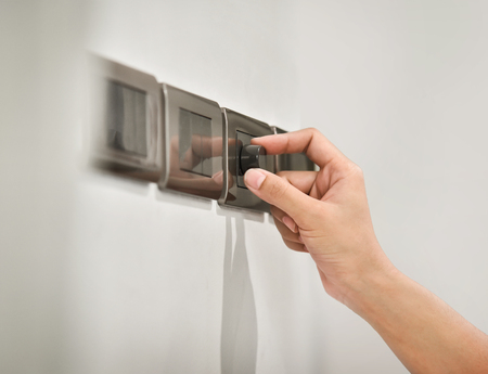Close up hand turning on grey light dimmer switch. Copy space.