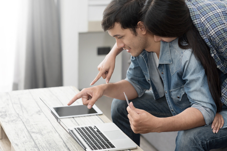Online shopping at home. Young couple holding credit card and using laptop computer together.の写真素材