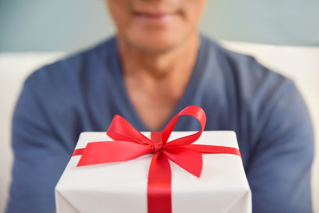 Happy Asian elderly man holding a white gift box. Birthday, Christmas and New year.の写真素材
