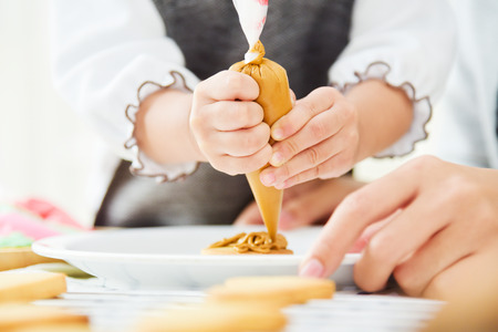 Close up on hands. Happy Asian Kid and young mother decorating cookies in the kitchen.の写真素材
