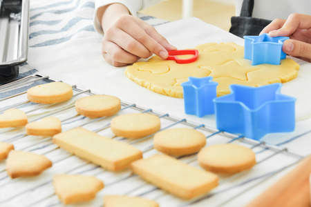 Asian girl and woman hands kneading and using cutters on dough. New year and Christmas cookies.の写真素材