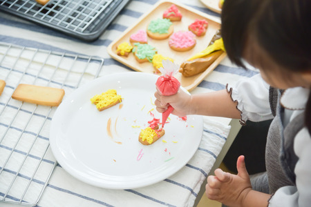 Happy Asian Kids decorating cookies in the kitchen.の写真素材