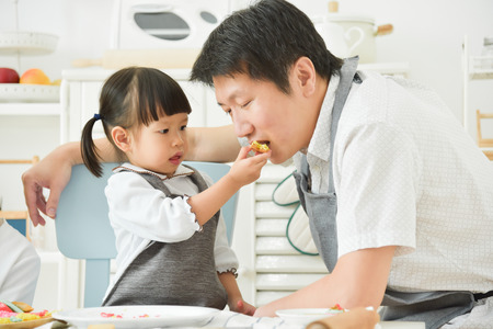 Asian Kids feeding a cookie to her father.の写真素材