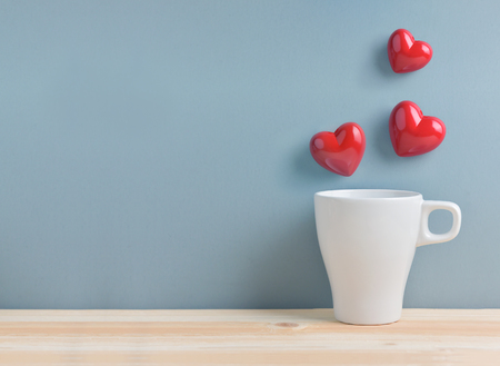 Valentines day. White cup of coffee with Red hearts on blue background. Copy space.の写真素材