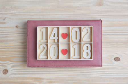Valentines day. Wooden block calendar show date, month and year with Two Red hearts on horizontal...
