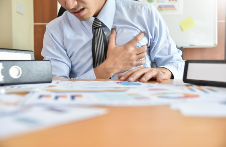 Young Asian Businessman having heart attack while he work overtime. Chest pain.