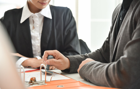 Businessman hand is stamping on document while discussing at meeting.