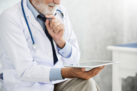 Close up Senior Male Doctor hands using  digital tablet computer. Medical and health concepts.の写真素材